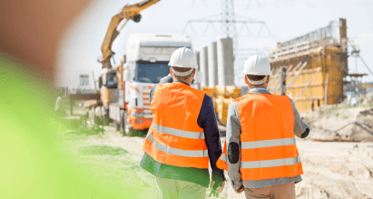 Bouwvakkers met veiligheidshelmen en hesjes op bouwplaats – ongevallenverzekering bouwbedrijf