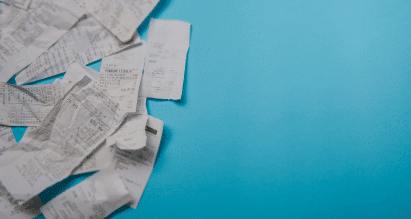 Stapel kassabonnetjes op een blauwe achtergrond als symbool voor aankoopbewijzen bij een schadeclaim.